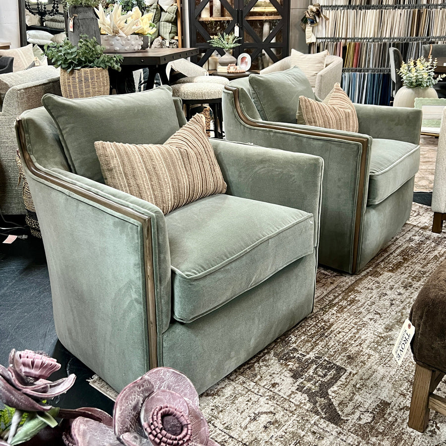 Light green armchairs with beige cushions in a store setting with books and decor.